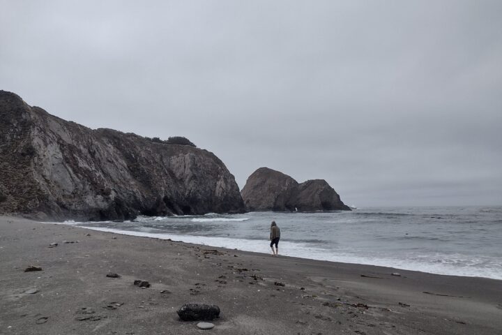 Greenwood beach on a cloudy day. One person can be seen walking along where the waves break