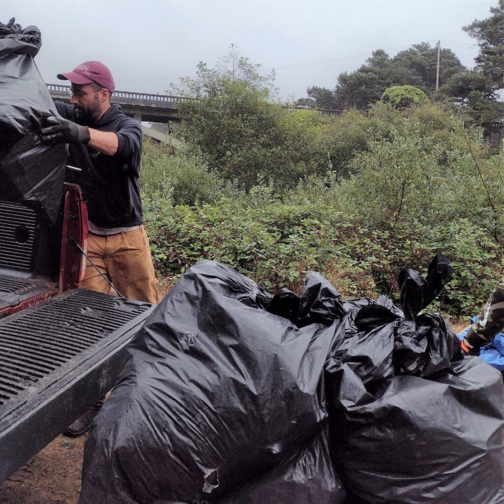 MLT's Ed Welter tosses trash bags into a truck at Hare Creek Beach