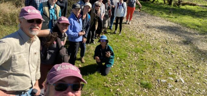 A photo of a group outdoors taken as a selfie by a man with a long arm